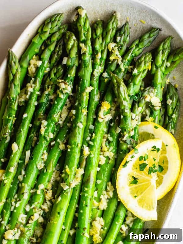 Lemon Garlic Asparagus served with lemon slices on an oval ceramic platter
