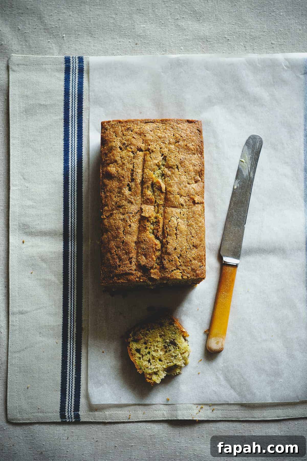 top down view of a zucchini bread on a table with a knife next to it