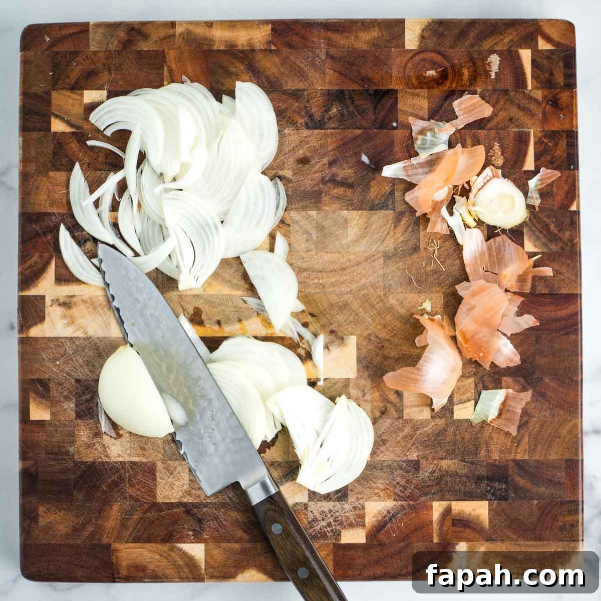 Thinly slicing an onion on a wooden board.