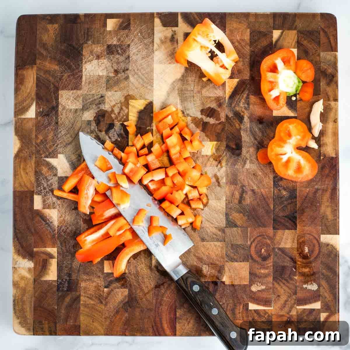 Showing how to dice a red bell pepper on a wooden cutting board.
