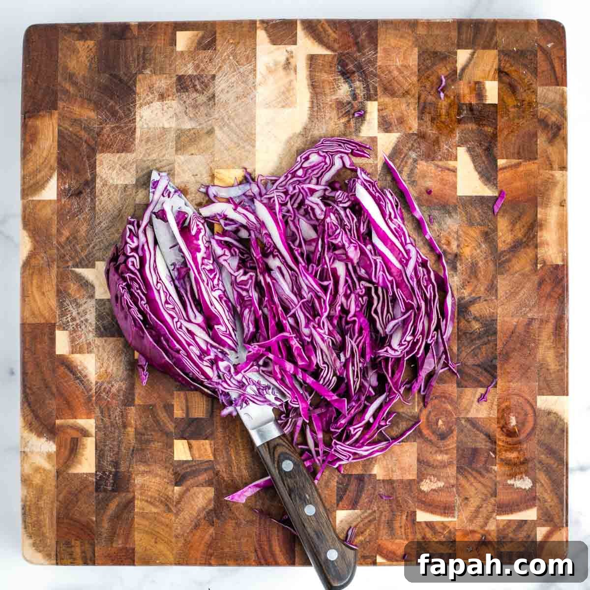 Showing how to thinly slice a quarter of a purple cabbage.