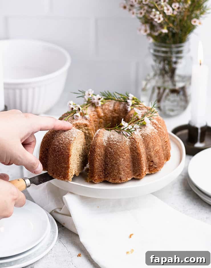 Close up of a hand taking a slice out of a bundt cake on a white plate.