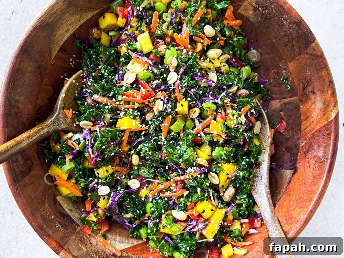 Rainbow salad being tossed in a bamboo serving bowl.