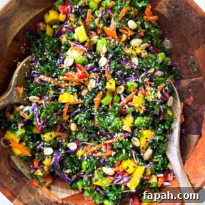 Rainbow salad in a bamboo bowl with bamboo serving spoons.