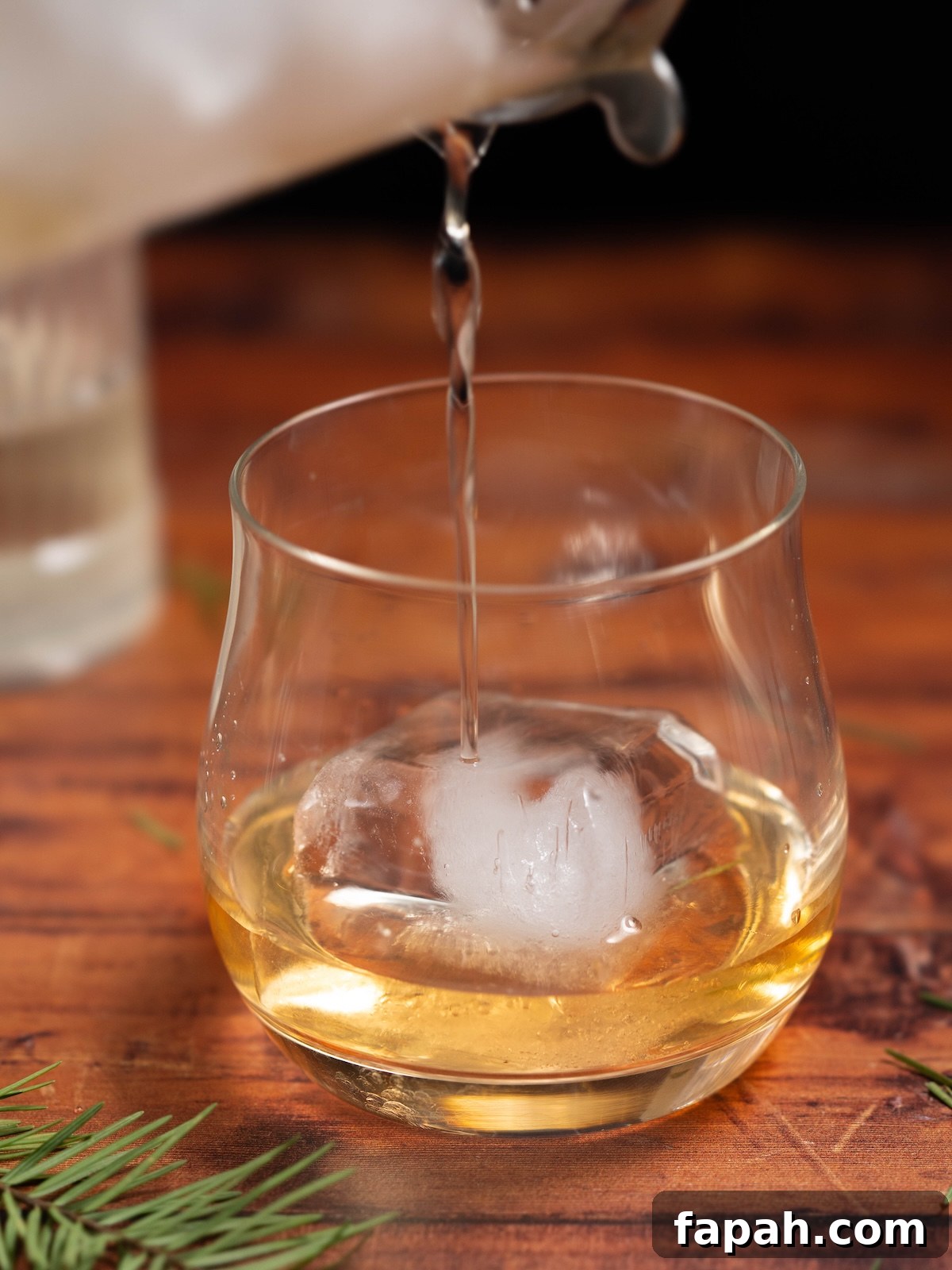 Pine Needle Old-Fashioned Cocktail Recipe Guide 4 Straining a cocktail into a lowball glass over a big cube