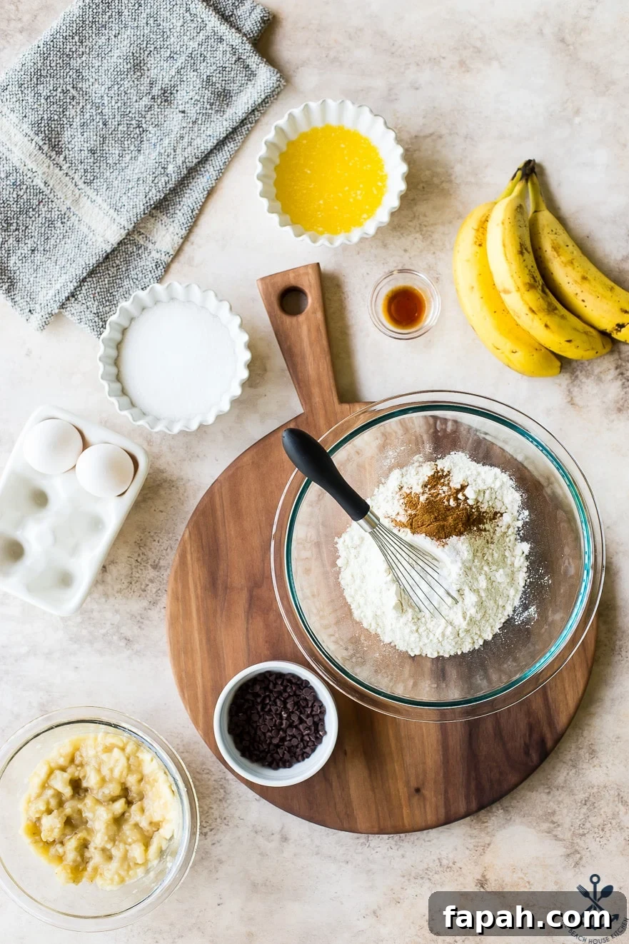 Chocolate Chip Banana Bread Waffles Recipe — Crispy Banana-Chip Waffles 6 Overhead photo of ingredients for chocolate chip banana bread waffles in bowls on a wooden board