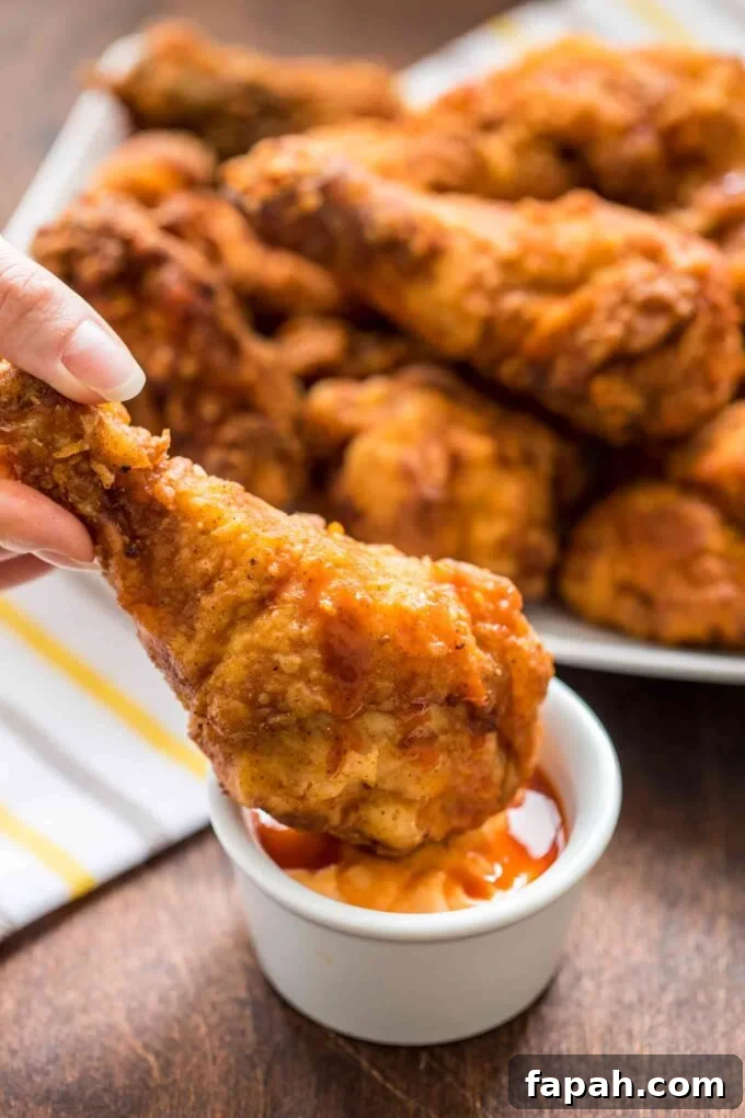Crispy Southern-Style Fried Chicken Recipe for Perfect Crunch 13 Dipping homemade fried chicken into a creamy sauce.
