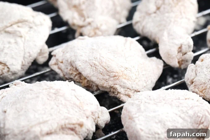 Crispy Southern-Style Fried Chicken Recipe for Perfect Crunch 8 Flour coated chicken pieces resting on a wire rack.