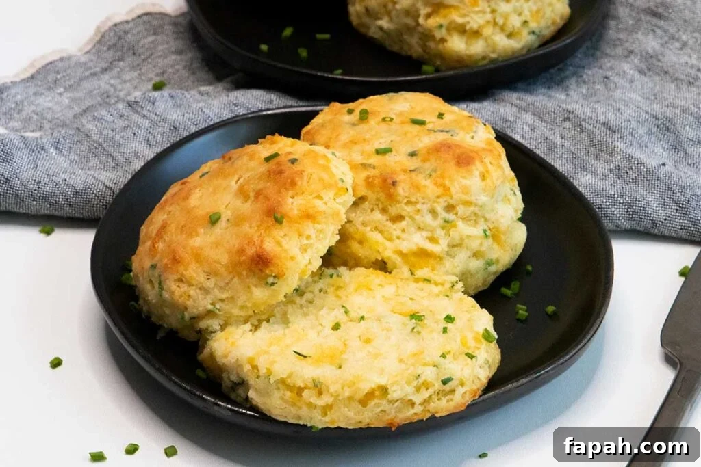 Cheddar chive biscuits on black plate.