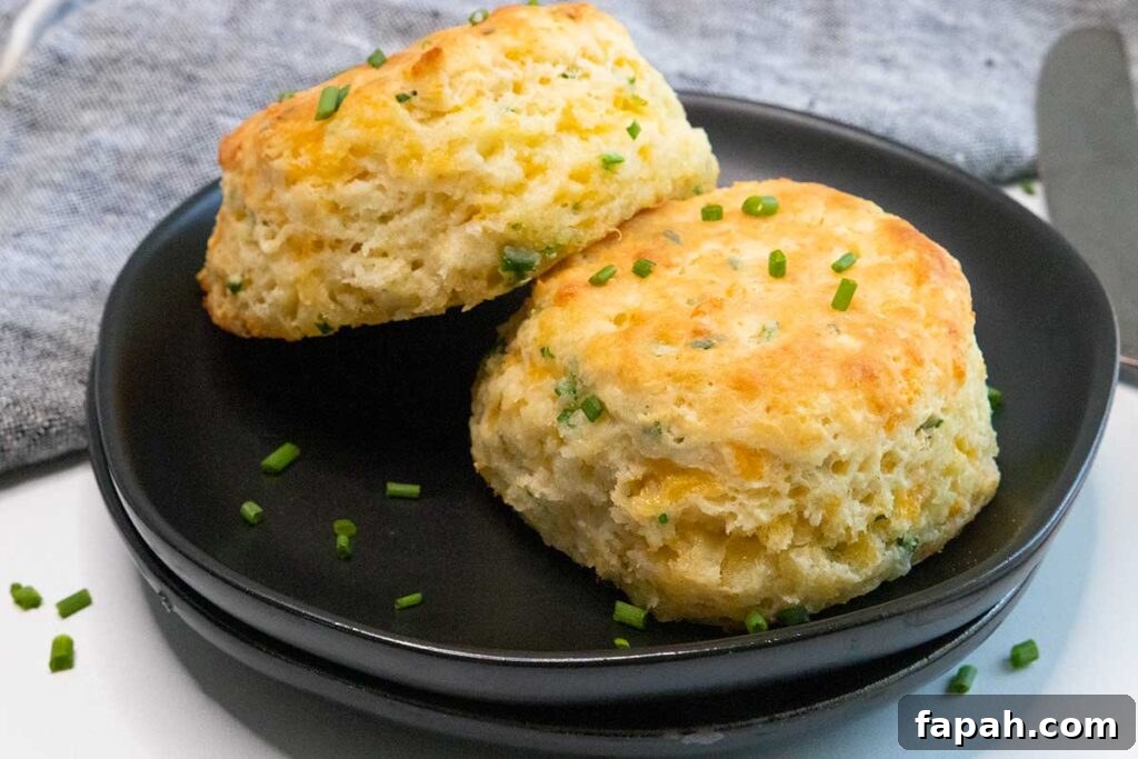 Cheddar chive biscuits on a black plate.