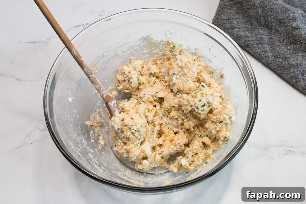 Cheddar chive biscuit dough in a glass mixing bowl.
