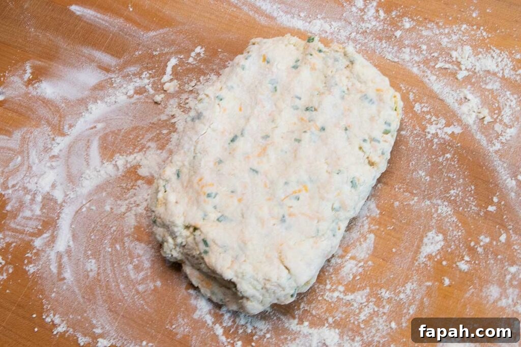 Cheddar chive biscuit dough on wooden cutting board.