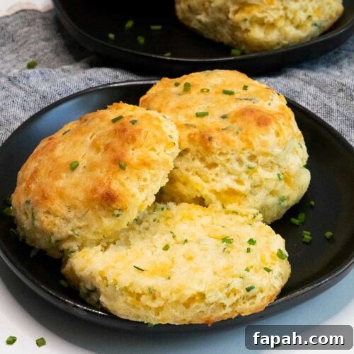 Cheddar chive biscuits on black plate.