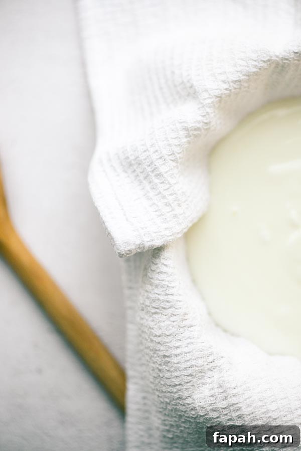 A bowl lined with a clean tea towel, filled with salted yoghurt ready for straining.