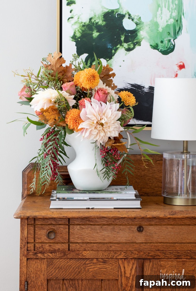 Complete Guide to Flower Arranging: Techniques, Tips & Styles 18 fall flower arrangement in a white pitcher on a wood table.