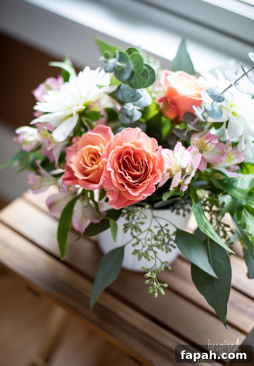 Complete Guide to Flower Arranging: Techniques, Tips & Styles 8 peach roses in a flower arrangement on a table.