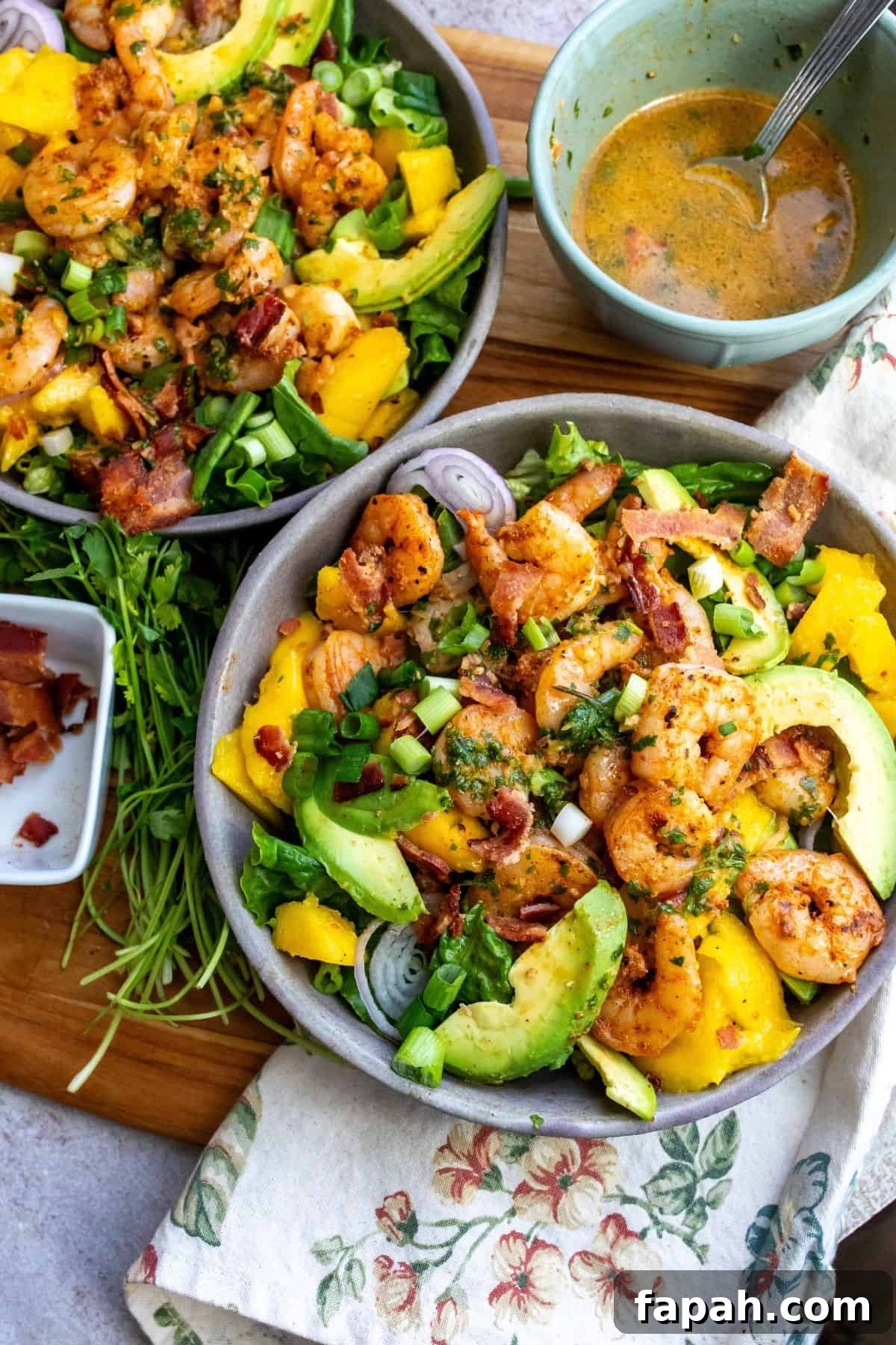 Grey bowl with mango, shrimp and salad in it. Cilantro to the side. 