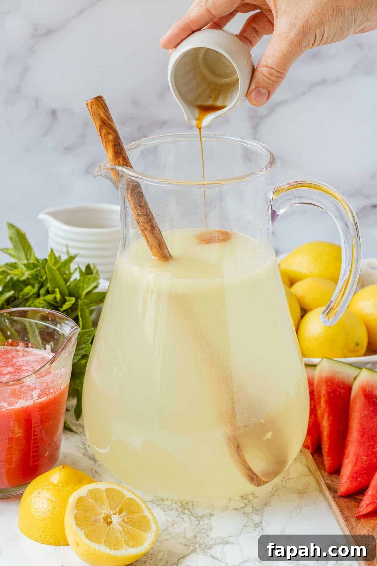 Pouring vanilla into pitcher of lemonade.