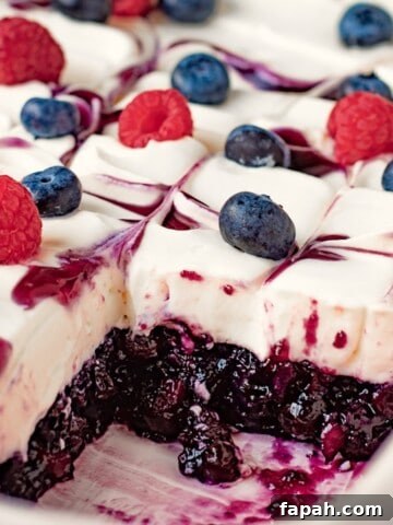 Blueberries and raspberries on whipped filling and sliced blueberry jello in white dish.