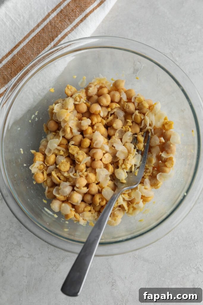 chickpeas smashed in glass bowl with fork and towel