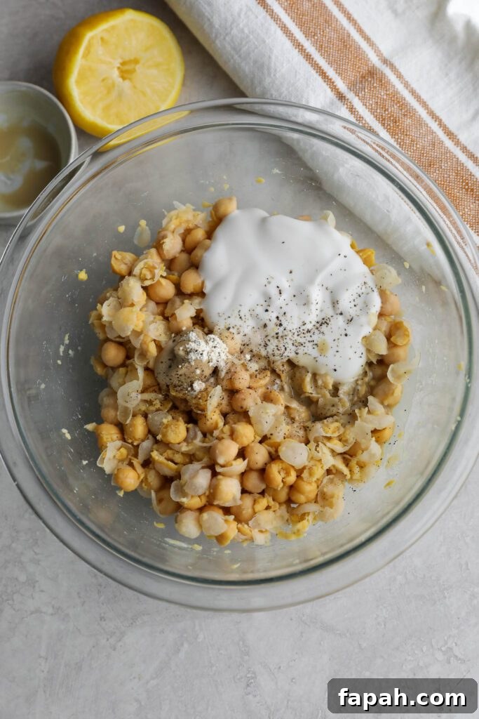 ingredients for chickpea salad mixed in glass bowl
