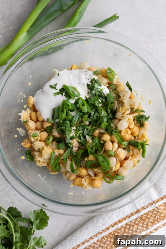 chickpea salad ingredients in bowl topped with cilantro and spring onion