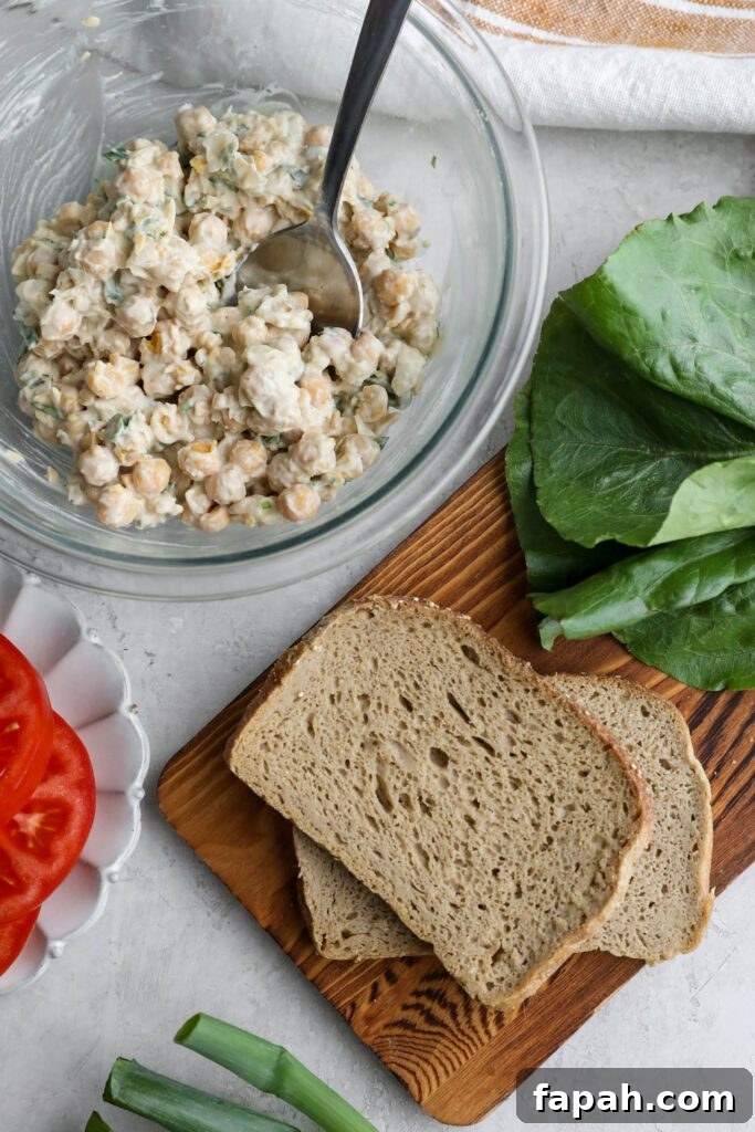 Vegan Chickpea Salad in bowl with board and lettuce and tomato