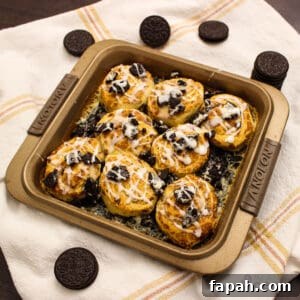 Finished oreo cinnamon rolls in baking pan on a kitchen towel with oreos around it.
