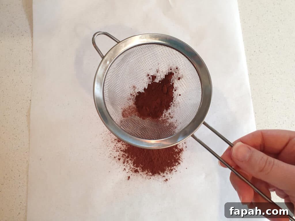 How to Make Homemade Oreo Cookies from Scratch 15 top down view sifting cocoa powder onto baking paper.