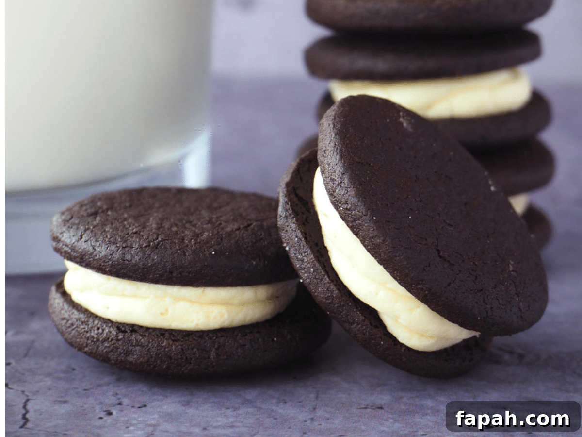 How to Make Homemade Oreo Cookies from Scratch 3 side view close up of two oreos, one proped on the other, with stack of homemade oreos, with glass of milk.