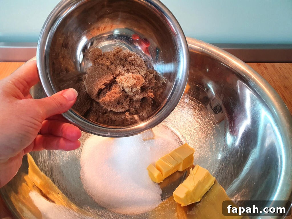 How to Make Homemade Oreo Cookies from Scratch 6 adding brown sugar to bowl with white sugar and butter in a large metal mixing bowl.