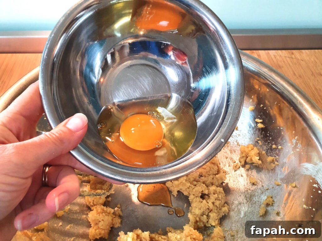 How to Make Homemade Oreo Cookies from Scratch 8 adding egg to butter, sugar and vanilla in a metal mixing bowl.