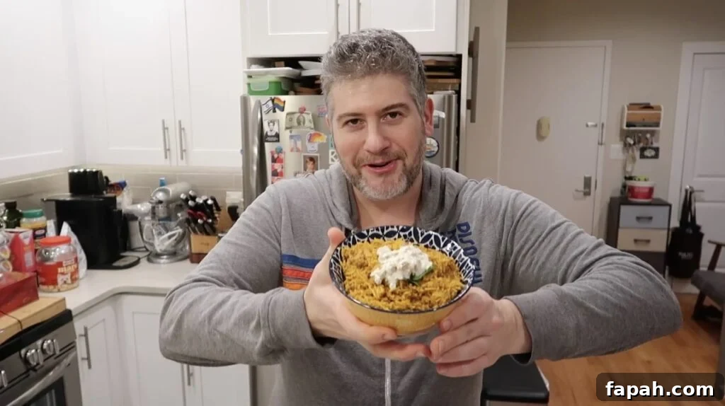 Man holding bowl of Chicken Biryani topped with cilantro and dill pickle dip