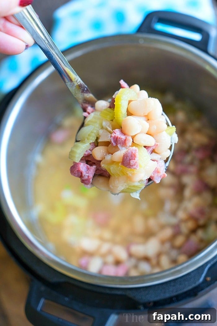 A spoonful of ham and bean soup held above a steaming pressure cooker.