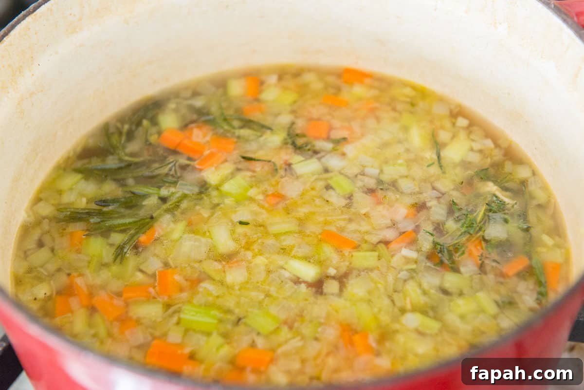 Creamy Spinach Tortellini Soup Recipe for Cozy Weeknights 7 Cooked Onion, Celery, Carrots, and Herbs in Pot