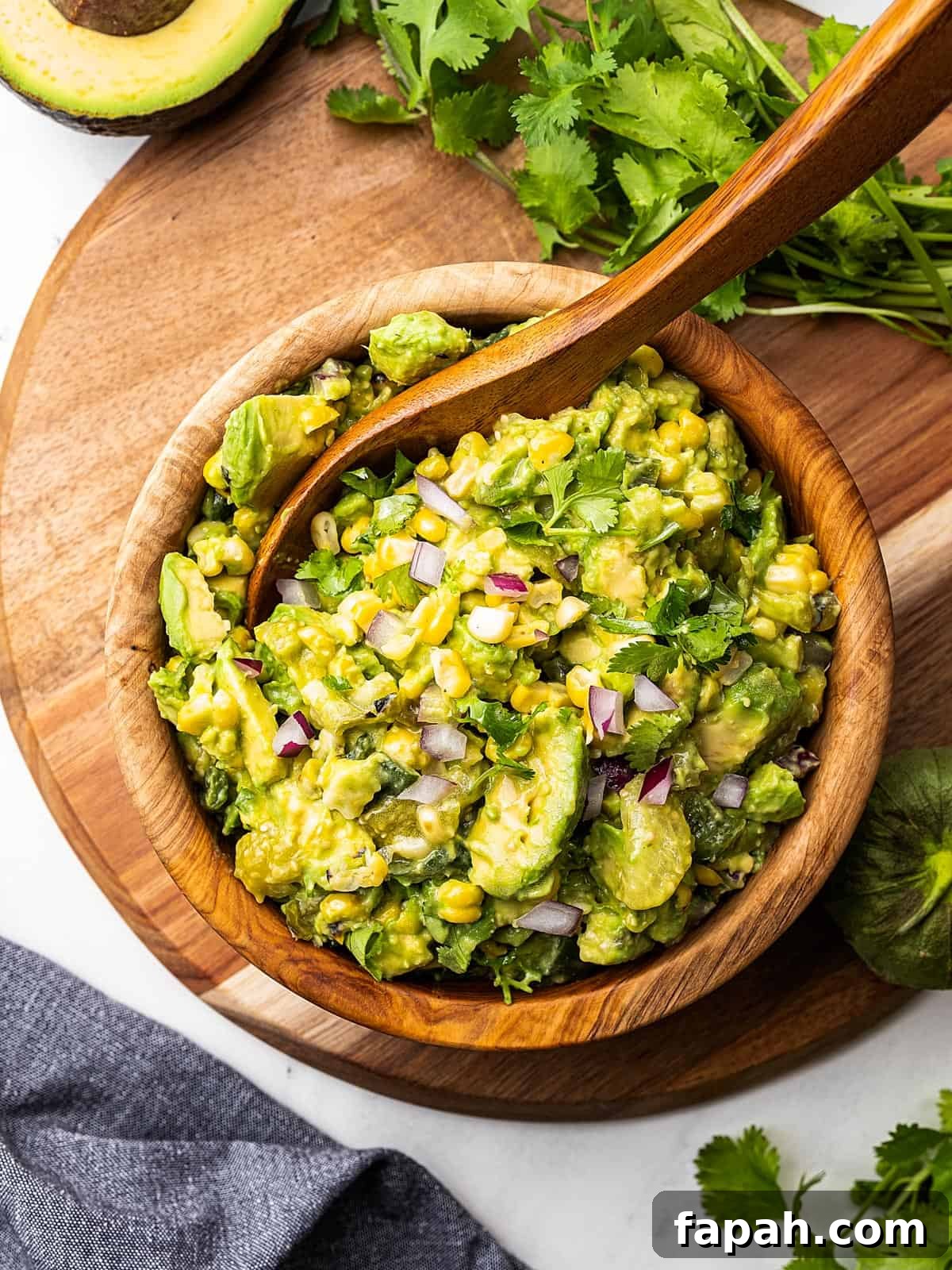 A wooden spoon stirring a bowl of homemade avocado green salsa