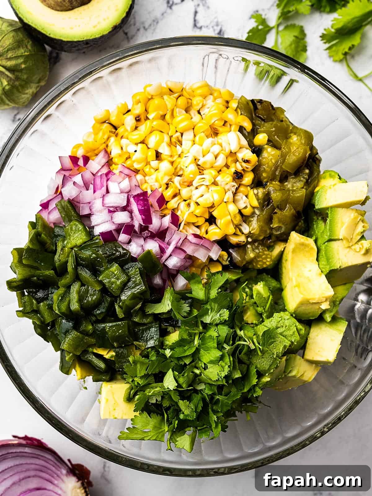 All of the tomatillo salsa ingredients inside of a glass mixing bowl