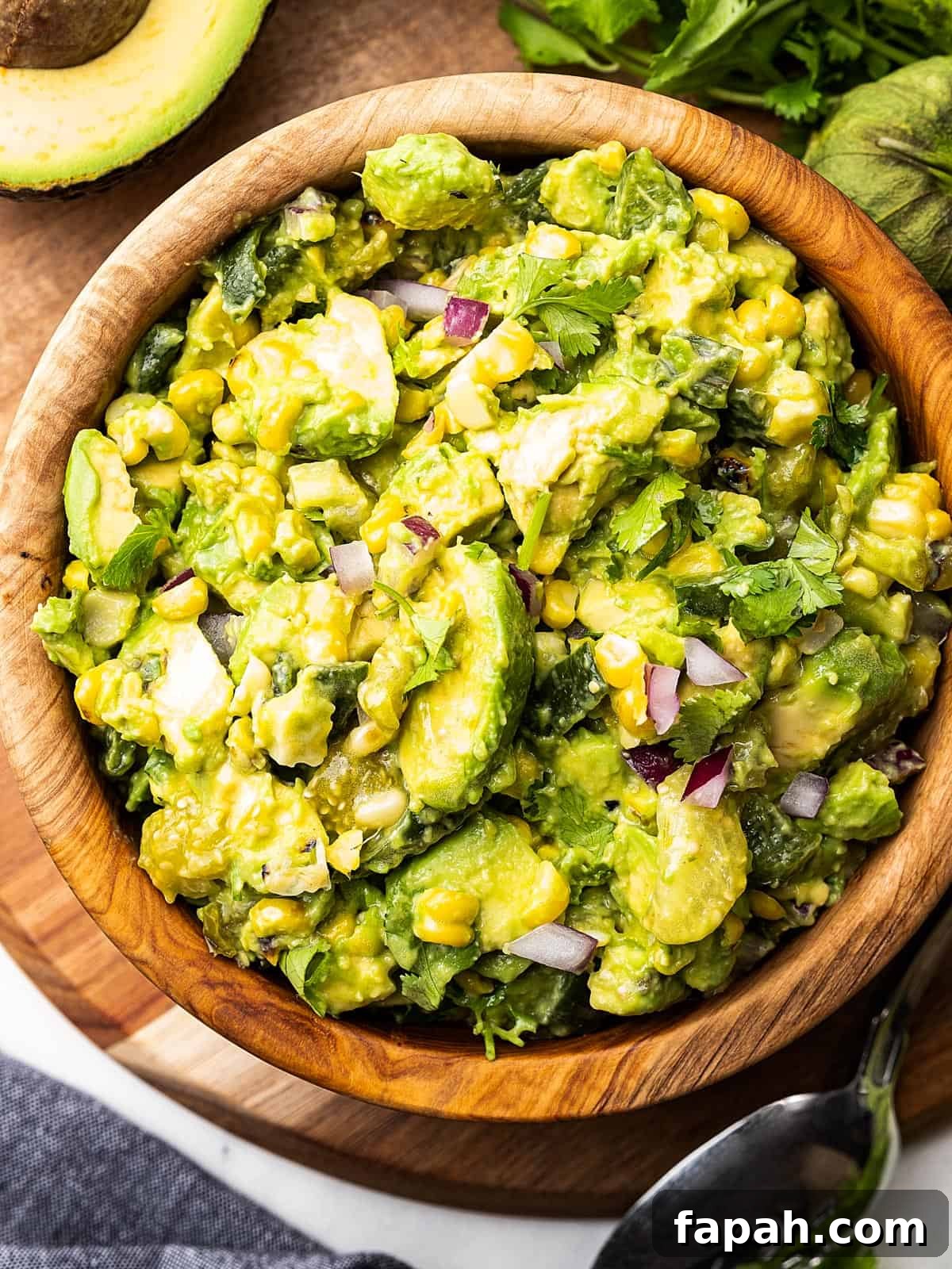 A bowl of avocado tomatillo salsa placed on top of a wooden cutting board