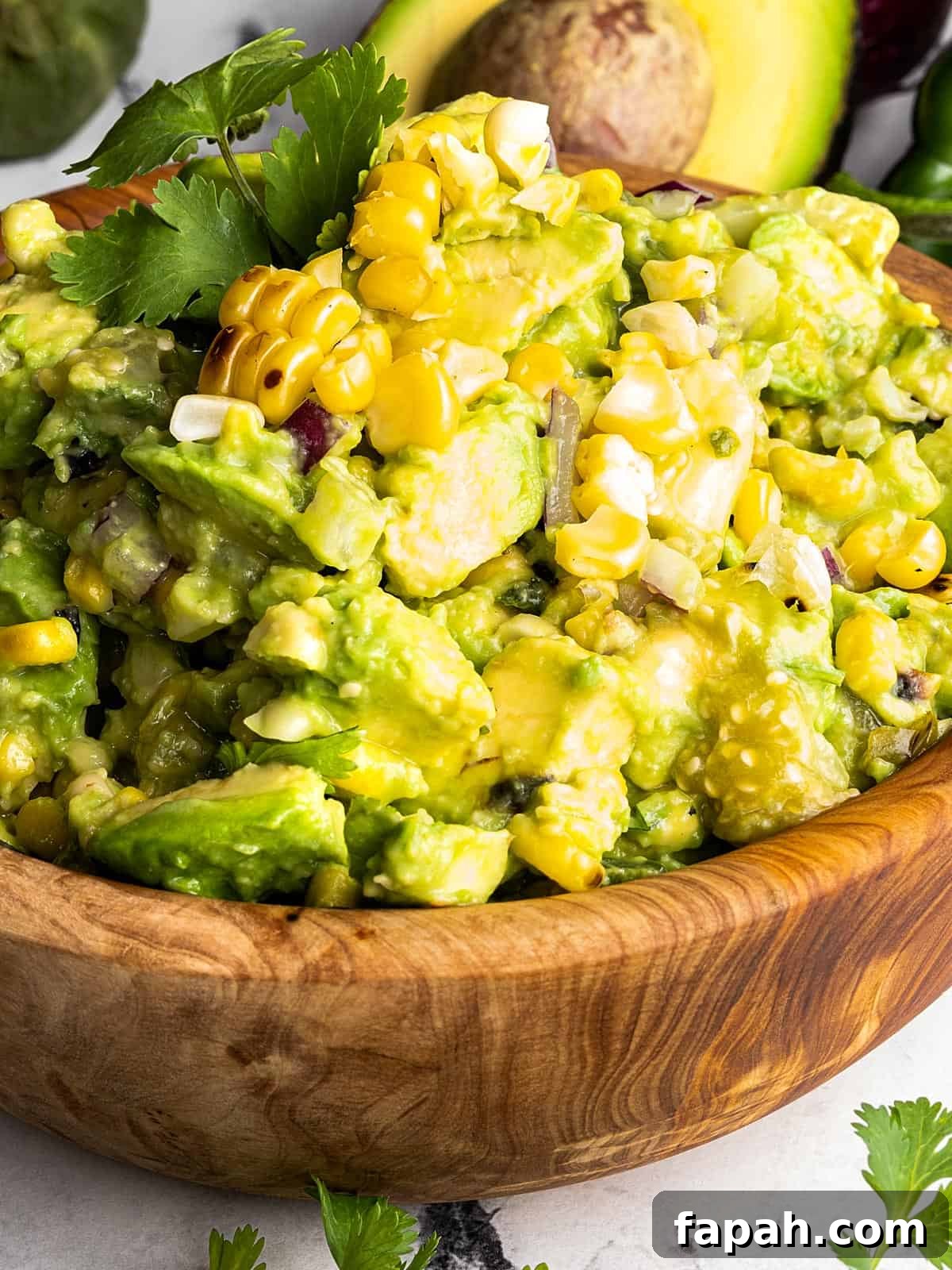 Avocado tomatillo salsa verde in a wooden bowl with a fresh sprig of cilantro on top