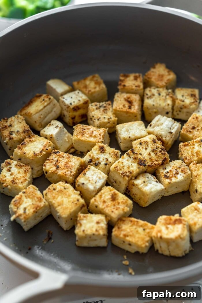 Crispy Orange Tofu Stir-Fry with Tangy Citrus Glaze 5 Crispy cubed tofu cooking in a pan.