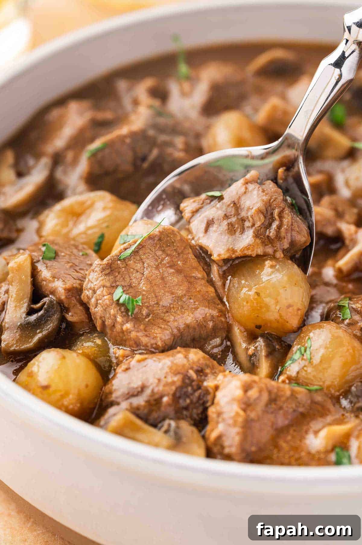 A close up view of a spoonful of slow cooker beef tips and gravy lifted from a bowl.