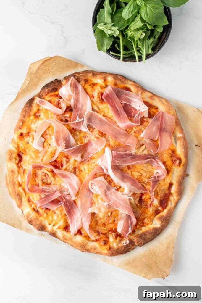 Cooked pizza with pieces of prosciutto on top.