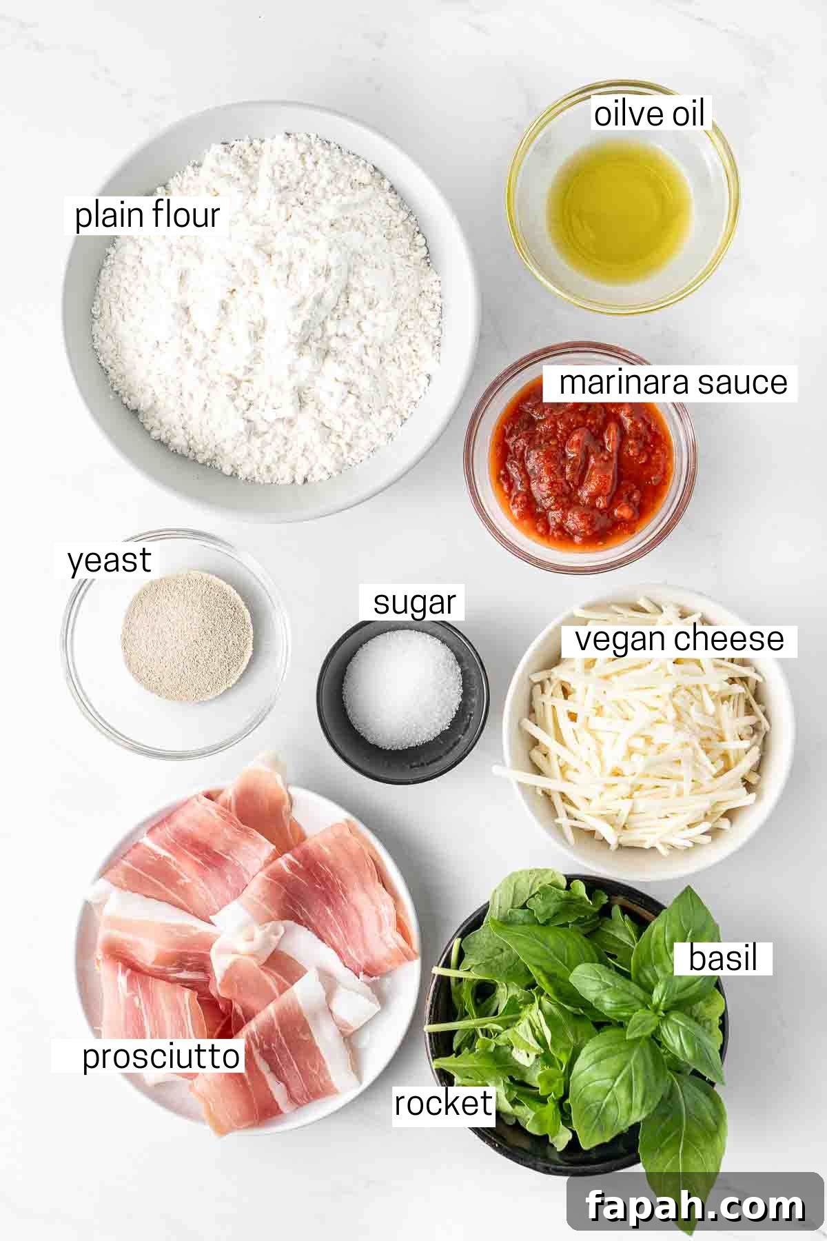 All ingredients needed to make prosciutto pizza laid out in small bowls.