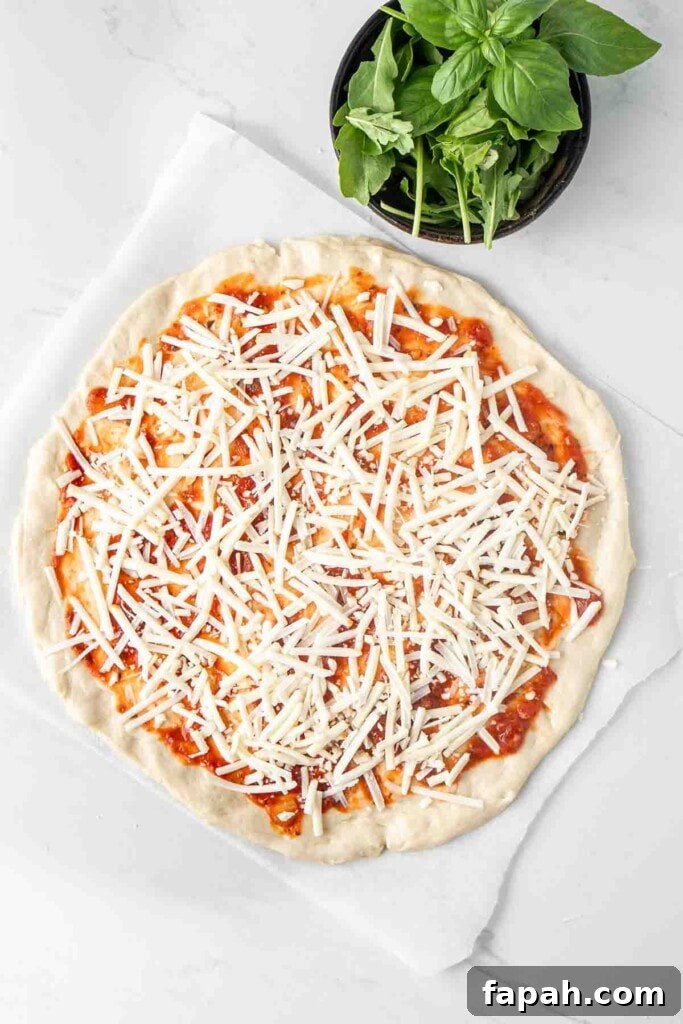 Making the pizza with sauce and cheese.