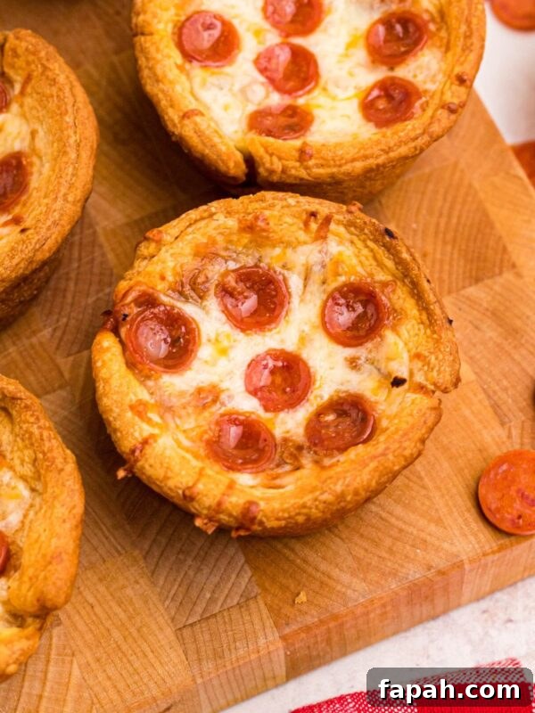 Baked Brie with Honey and Pecans: Warm Party Appetizer 11 Golden crusted pizza cupcakes on a wooden cutting board with pepperoni scattered around the table.