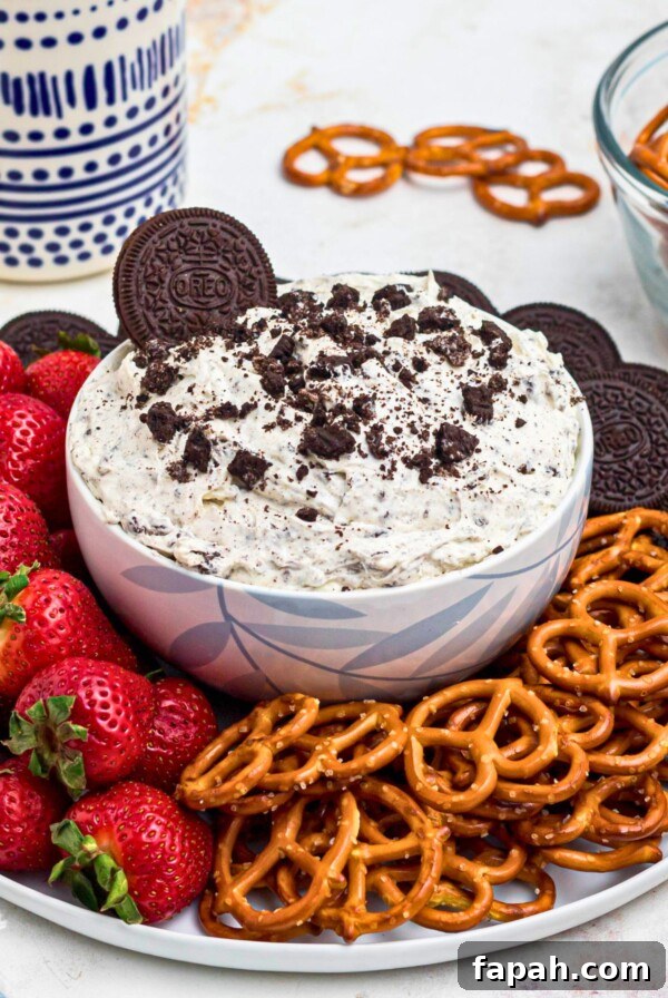 Baked Brie with Honey and Pecans: Warm Party Appetizer 12 Strawberries, pretzels, and chocolate cookies, on a round white plate, around a cookies and cream Oreo dip, on a marble table.