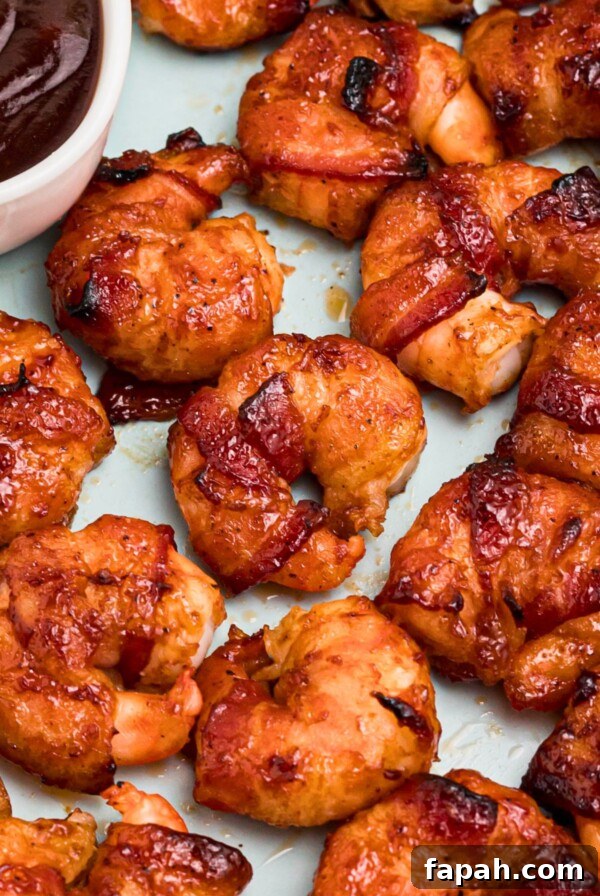 Baked Brie with Honey and Pecans: Warm Party Appetizer 13 Crispy bacon wrapped around shrimp, coated with BBQ sauce mixture, on a light green plate with lemon slices and serving tongs on the table.