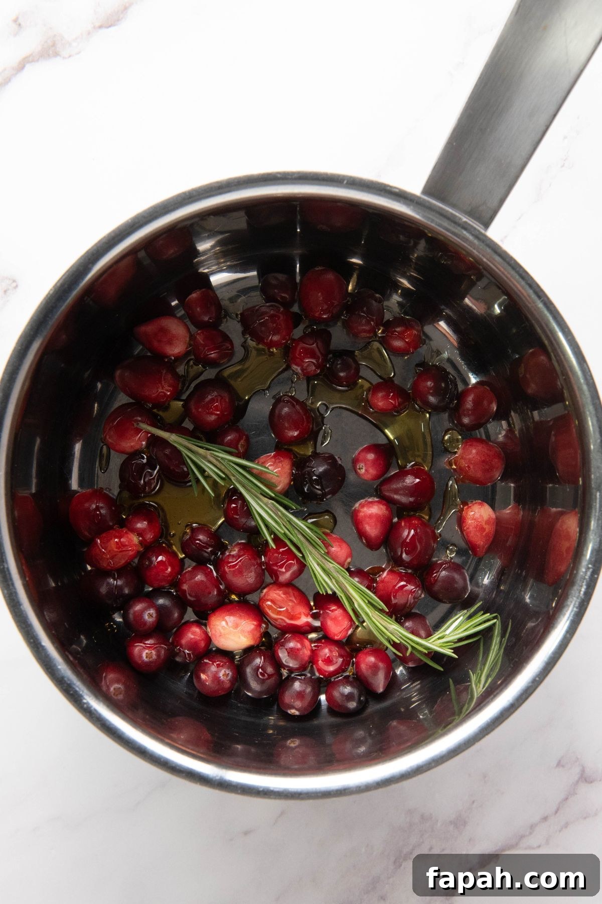 Baked Brie with Honey and Pecans: Warm Party Appetizer 6 Cranberries, sugar, and other ingredients being cooked in a small saucepan.