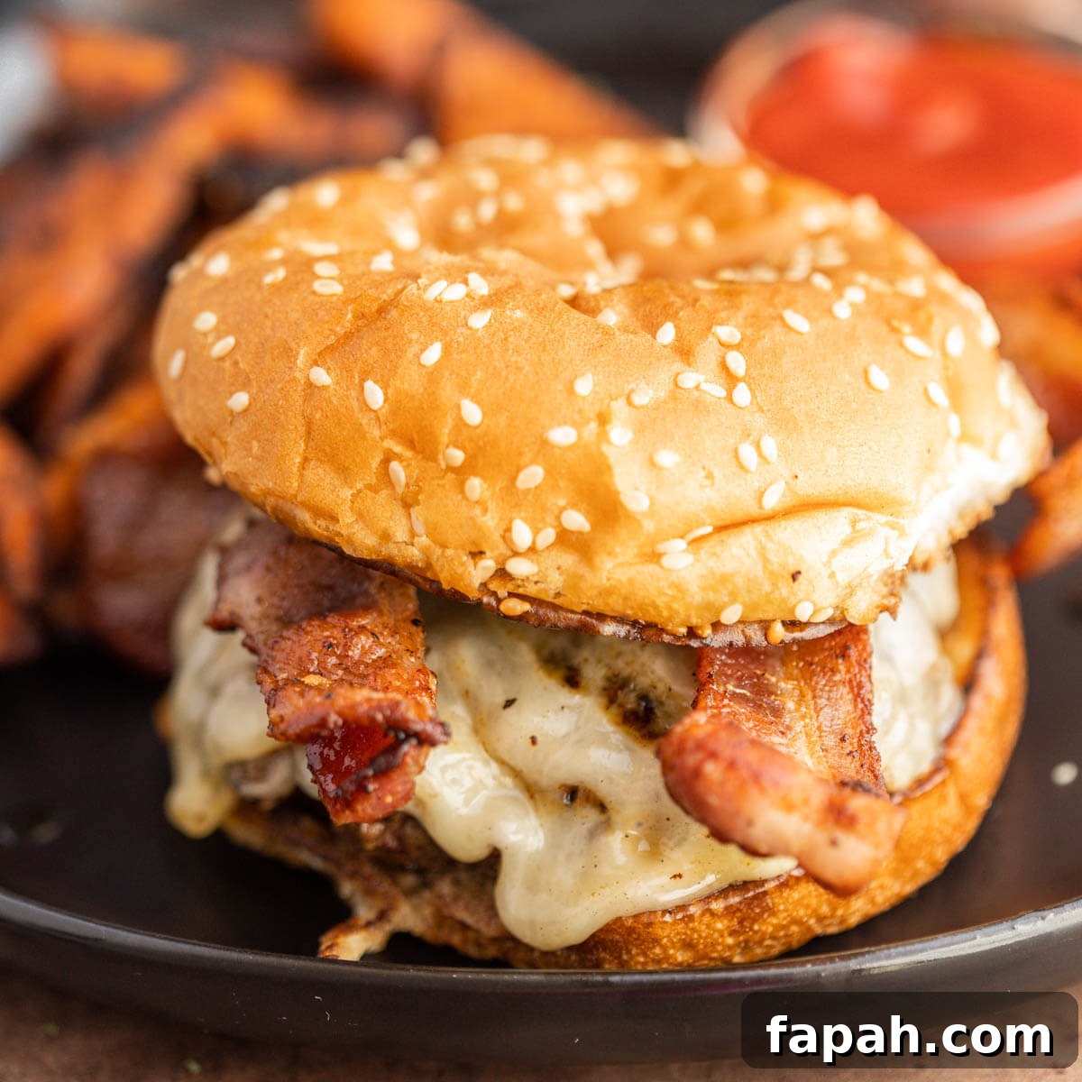 Bacon Cheeseburger on a plate with sweet potato fries.