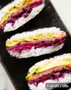 close up shot of 3 salmon sushi sandwiches on black serving plate